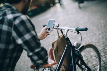 Man using smartphone while riding bicycle in city