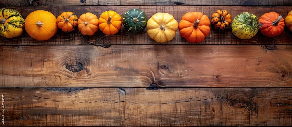 Fototapete pumpkins in various colors placed on the border of a wooden table set against a backdrop providing r
