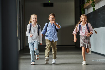 Obraz premium group of young children joyfully walking down a bright hallway