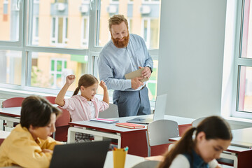 A passionate male teacher stands before a diverse group of engaged students in a vibrant classroom setting, delivering a captivating lesson.