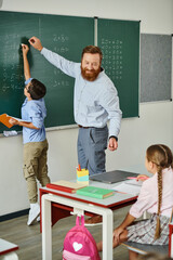 A male teacher stands confidently in front of a blackboard, passionately educating a group of...