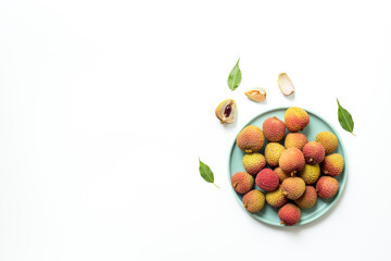 Juicy fresh lychee fruit with cut in half and green leaves on the plate, top view