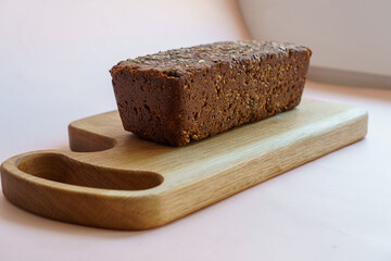 classic sourdough artisan rye black with seeds bread on a wooden board on a pastel pink background.