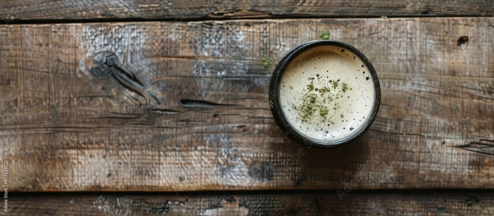 Poster Top view of a coffee cup with frothy matcha on a wooden surface in flat lay style featuring copy space image