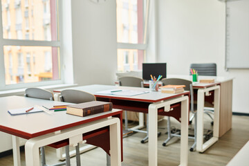 The classroom sits empty, desks and chairs aligned in neat rows