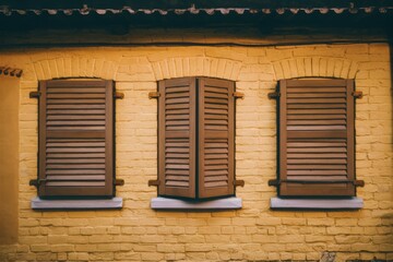 A brick wall with three windows and a clock on it, AI