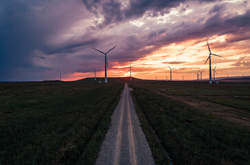 Obraz premium Wind turbines at sunset on a rural road