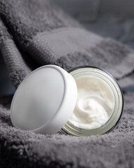 White opened cosmetic jar with white blank lid on grey folded towels in bath, packaging mockup