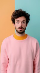 Fototapeta premium Surprised Young Man in Colorful Sweater Standing Against a Split Pastel Background