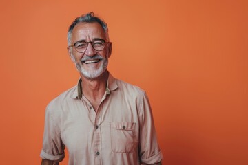 Fototapeta premium Portrait of a happy man in his 50s wearing a simple cotton shirt isolated in solid color backdrop