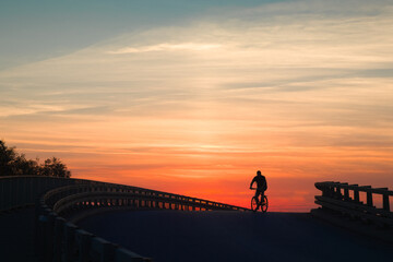 silhouette of a cyclist on a bridge