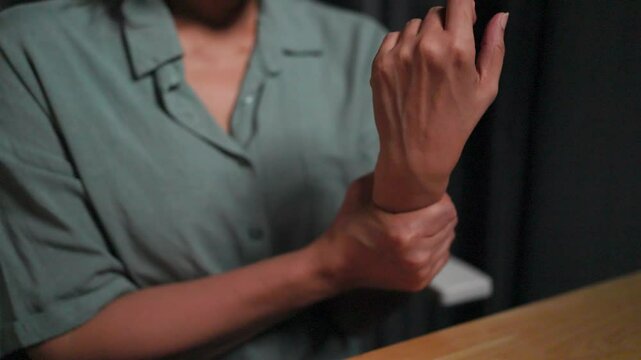 Close-up of woman massaging her aching arm and wrist, Asian woman typing on laptop at home Working overtime at night Working until injured and meeting deadlines. Writer of stories and articles.