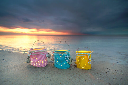 lapms with burning candles on the beach in sunset