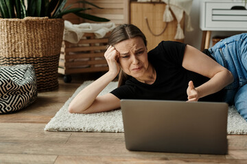 A woman in introspection, lying on the floor fixated on her laptop screen.