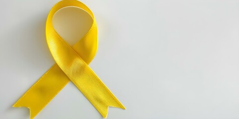 Yellow ribbon on white background symbolizing endometriosis and childhood cancer awareness campaign. Concept Endometriosis Awareness, Childhood Cancer Awareness, Yellow Ribbon, White Background