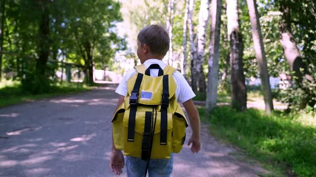 A first-grader boy walks or runs to school on the first bell on September 1