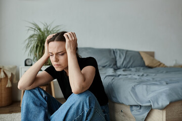 Middle-aged woman in distress, sitting on floor with hands on head.