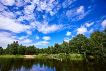Beautiful summer river at sunny day with clouds reflection in the water