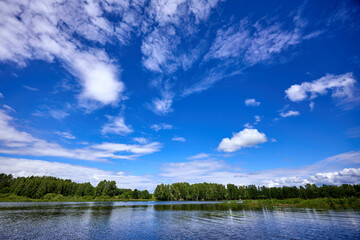 Beautiful summer river at sunny day with clouds reflection in the water