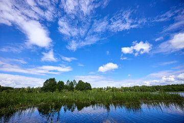 Beautiful summer river at sunny day with clouds reflection in the water