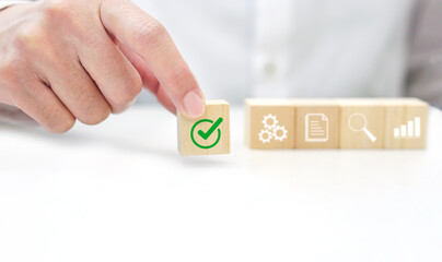 Hand holding a wooden block cube with check mark icon symbol. Business strategy, data verification...