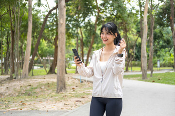 Young woman walking and listening to music at the park.