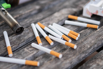 Scattered cigarettes and lighter on wooden surface