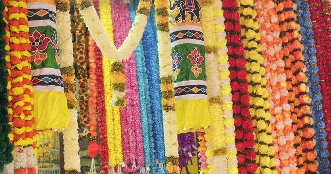 Multicolored garlands with flowers hang on the street in the Indian Quarter in Malaysia. Hindu religious symbol, yellow flowers. Preparation for the wedding ceremony. Fresh flower arrangements, decor