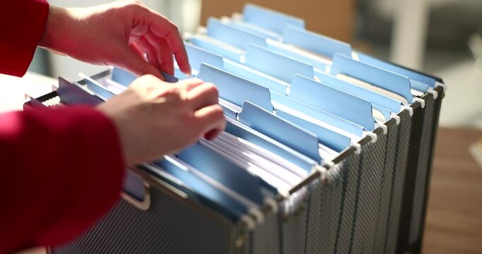Secretary looks for necessary folder with accounting papers for analysis. Woman checks organized archive materials in office drawer slow motion
