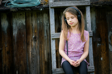 Fototapeta premium Sad portrait of a rural teenage girl with headphones.