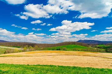 Fototapeta premium Scenic view of rolling hills under a vibrant blue sky with fluffy clouds. West Virginia
