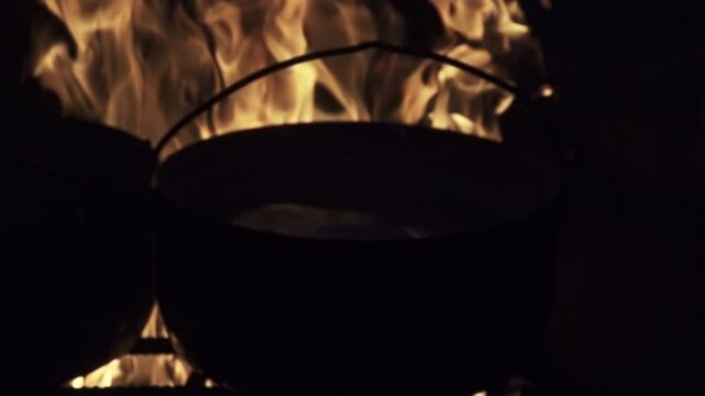 Boiling boilers. Against the background of flames at night. This is like medieval cauldrons of repelling fortress attacks and inquisition torments. Super slow motion 1000 fps.
