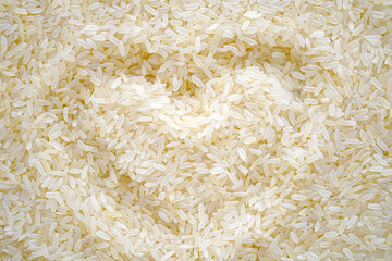 Uncooked rice with heart shape background. Parboiled rice texture backdrop. Cooking preparation in the kitchen concept.