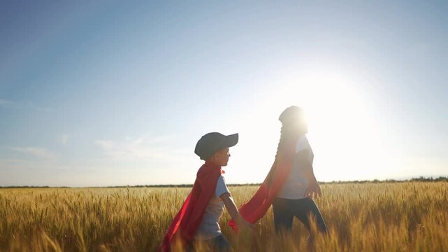 A group of kids playing a video game of superheroe together. Child hero fun concept. Superhero running through the wheat with children. A group of kids playing a game sunset of running together.