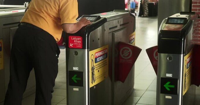 View of the turnstile in the metro, access system for security in underground transport. The man approaches the automatic gate and scans his access card and goes through the doors inside.