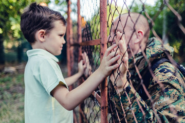 Dad returns home from overseas military assignment. Happy military father meeting with son after mission.