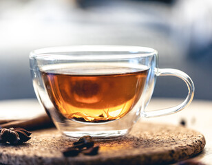 Close-up, glass cup of aromatic black tea on a blurred background.