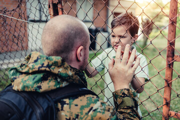 Dad returns home from overseas military assignment. Happy military father meeting with son after mission.