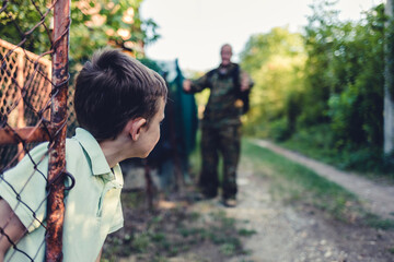 The dad is leaving for overseas assignment. The boy standing in front of the gate and sending his father off on an overseas assignment.