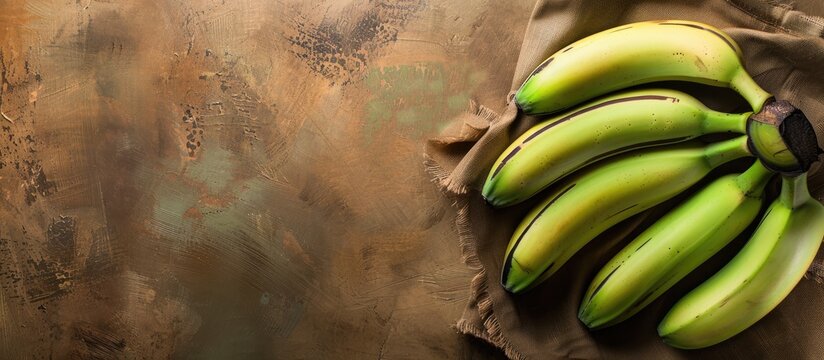 Green unripe bananas showcased on a warm toned brown backdrop with ample copy space image