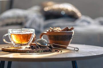 Tea ceremony, glass cup of black tea and teapot on blurred home background.