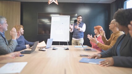 Business team applauding a colleague's presentation in a modern meeting room.