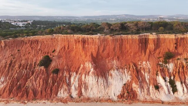 Flying along the red-colored cliffs of Praia da Falesia in Portugal at sunset