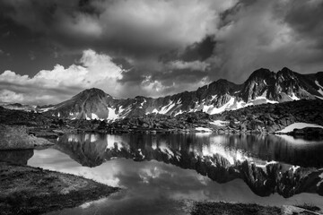 Photo en noir et blanc d'un lac de montagne dans les Pyrénées Andorranes avec encore des névés...
