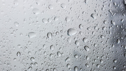 Detail of water droplets, gloomy gray day. Window and rain outside