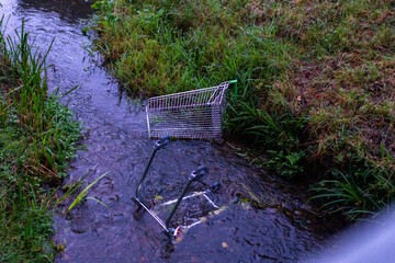 Abandoned shopping trolley in a public park river, Cheltenham, UK