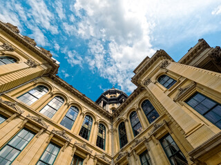 Looking up at the dome of the Illinois State Capitol Building in Springfield, Illinois, USA. Partial side view of the building set against a cloudy blue daytime sky. Captured while congress in session