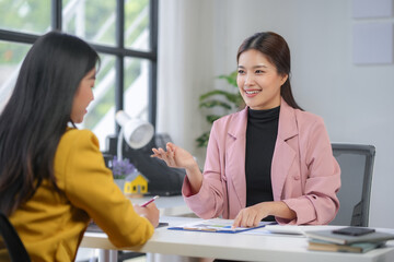 Two businesswomen are discussing financial charts in a modern office, showing teamwork and collaboration in a corporate setting