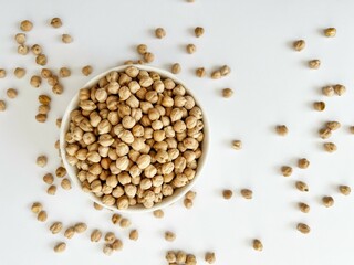 Raw dry chickpea in small ceramic bowl on white background. Traditional ingredient for cooking hummus. Middle Eastern and Mediterranean cuisine. Selected focused