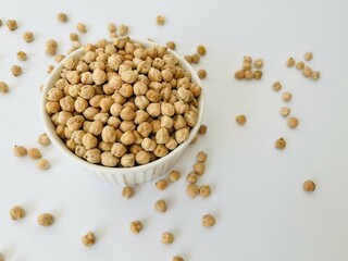 Raw dry chickpea in small ceramic bowl on white background. Traditional ingredient for cooking hummus. Middle Eastern and Mediterranean cuisine. Selected focused